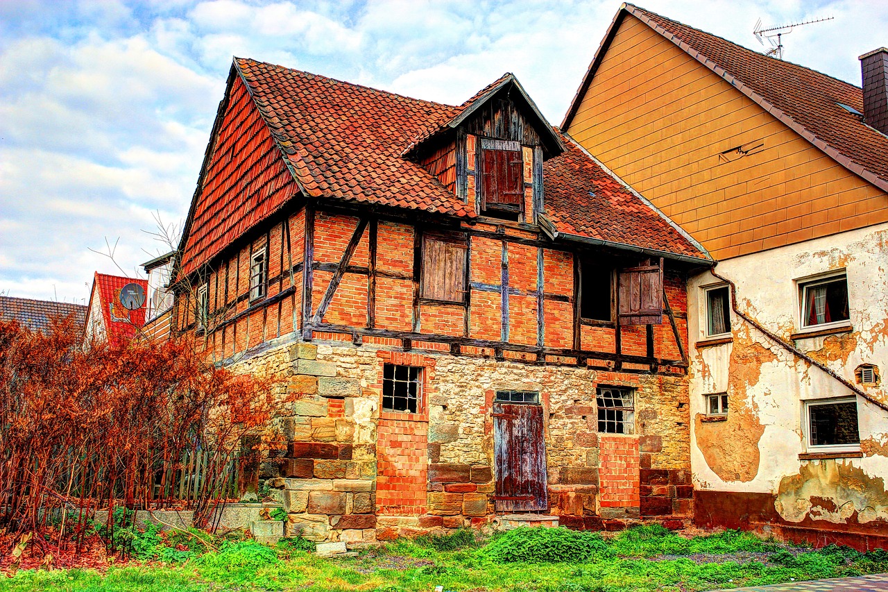A photograph of an old European house, with different portions of the facade build from distinct materials, such as stone, red brick, white brick.